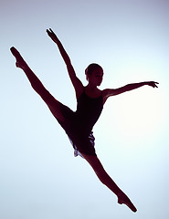 Image showing Beautiful young ballet dancer jumping on a gray background. 