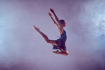 Image showing Beautiful young ballet dancer jumping on a lilac background. 