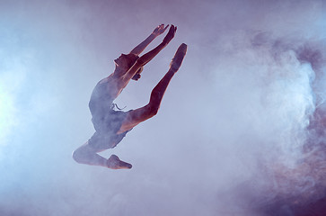 Image showing Beautiful young ballet dancer jumping on a lilac background. 