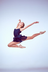 Image showing Beautiful young ballet dancer jumping on a gray background. 