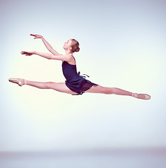 Image showing Beautiful young ballet dancer jumping on a gray background. 