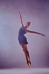 Image showing Beautiful young ballet dancer jumping on a lilac background. 