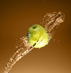 Image showing Green apple with water splash, on beige