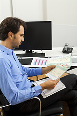 Image showing Young man reading written agreements for work