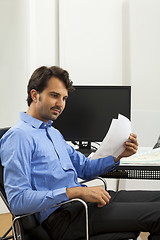 Image showing Young man reading written agreements for work