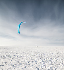 Image showing Kiteboarder with blue kite on the snow