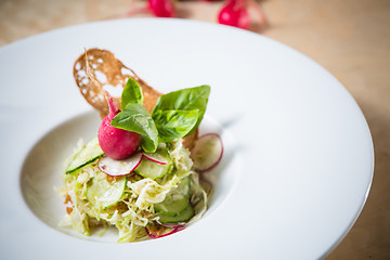 Image showing Salad from cabbage, herbs, cucumber and radish in bowl.