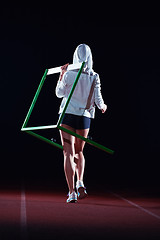 Image showing woman athlete jumping over a hurdles