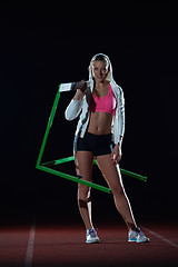 Image showing woman athlete jumping over a hurdles