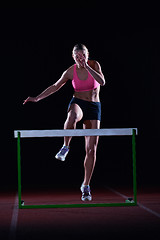 Image showing woman athlete jumping over a hurdles