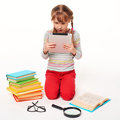 Image showing Girl with a lot of books reading digital tablet