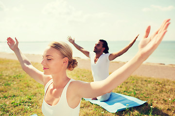 Image showing smiling couple making yoga exercises outdoors