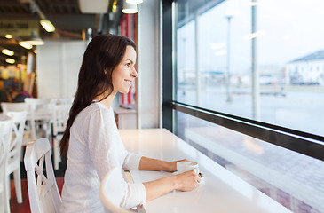 Image showing smiling young woman drinking coffee at cafe