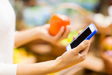 Image showing woman with smartphone and persimmon in market