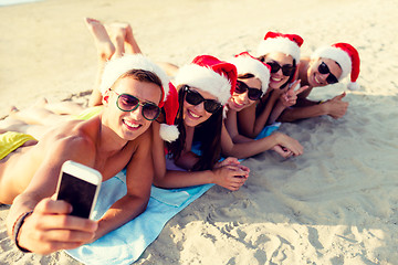 Image showing group of friends in santa hats with smartphone