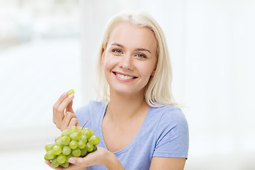 Image showing happy woman eating grapes at home
