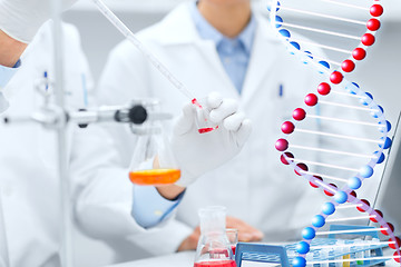 Image showing close up of scientists filling test tube in lab