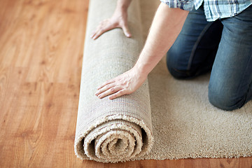 Image showing close up of male hands rolling carpet