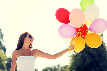 Image showing smiling young woman in sunglasses with balloons