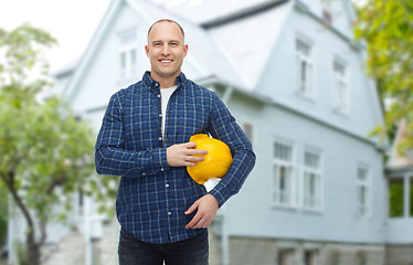 Image showing smiling man holding helmet over house background