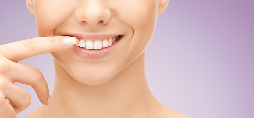 Image showing close up of smiling woman face pointing to teeth