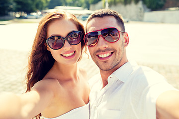 Image showing smiling couple wearing sunglasses making selfie