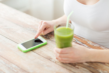 Image showing close up of woman with smartphone and green juice