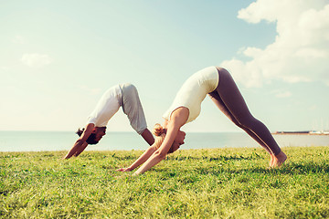 Image showing smiling couple making yoga exercises outdoors