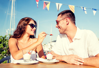 Image showing smiling couple eating dessert at cafe