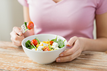 Image showing close up of young woman eating salad at home