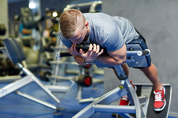 Image showing young man flexing back muscles on bench in gym