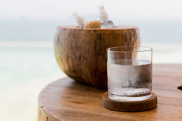 Image showing glass of water and moisturizers on table at beach