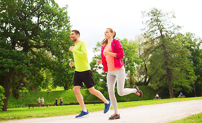 Image showing smiling couple with earphones running outdoors