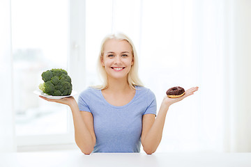 Image showing smiling woman with broccoli and donut at home