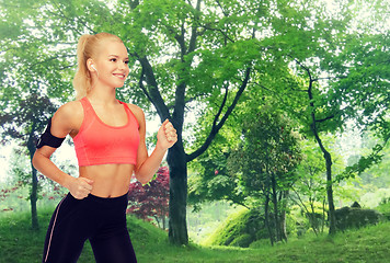 Image showing sporty woman running with smartphone and earphones