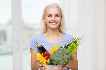 Image showing smiling young woman with vegetables at home