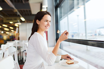 Image showing smiling young woman with cake and coffee at cafe