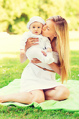 Image showing happy mother with little baby sitting on blanket