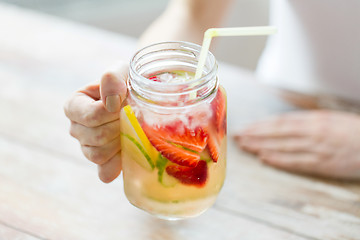 Image showing close up of woman holding glass with fruit water