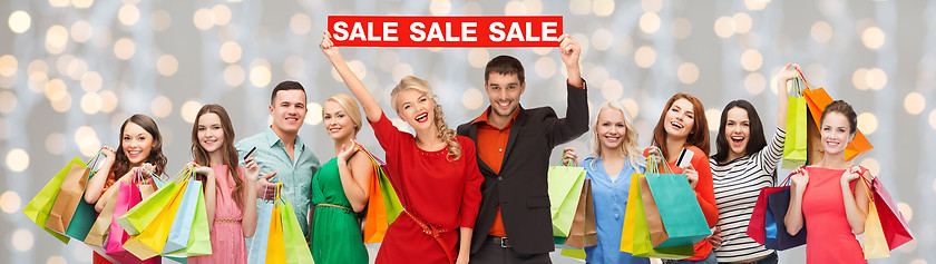 Image showing happy people with red sale sign and shopping bags
