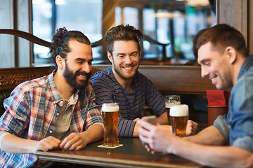 Image showing male friends with smartphone drinking beer at bar