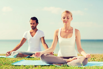 Image showing smiling couple making yoga exercises outdoors