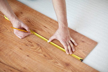 Image showing close up of male hands measuring flooring