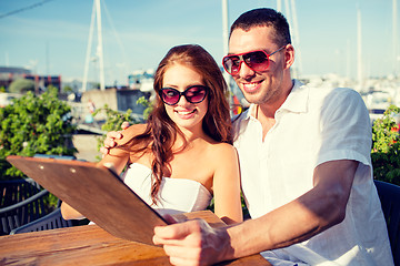 Image showing smiling couple with menu at cafe