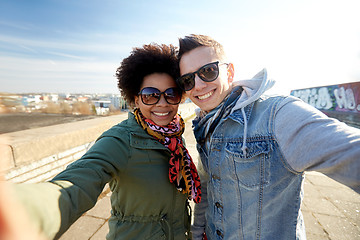 Image showing happy teenage couple taking selfie on city street