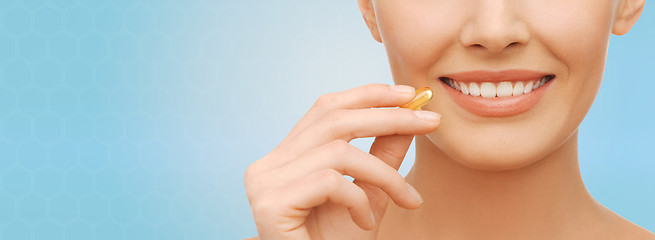 Image showing beautiful woman holding omega 3 vitamins capsule