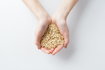 Image showing close up of woman hands holding oatmeal flakes