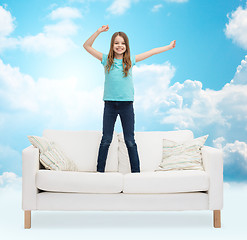 Image showing smiling little girl jumping on sofa