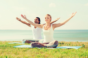 Image showing smiling couple making yoga exercises outdoors