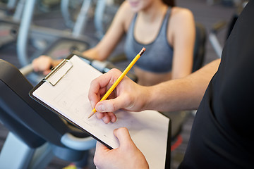 Image showing close up of trainer hands with clipboard in gym